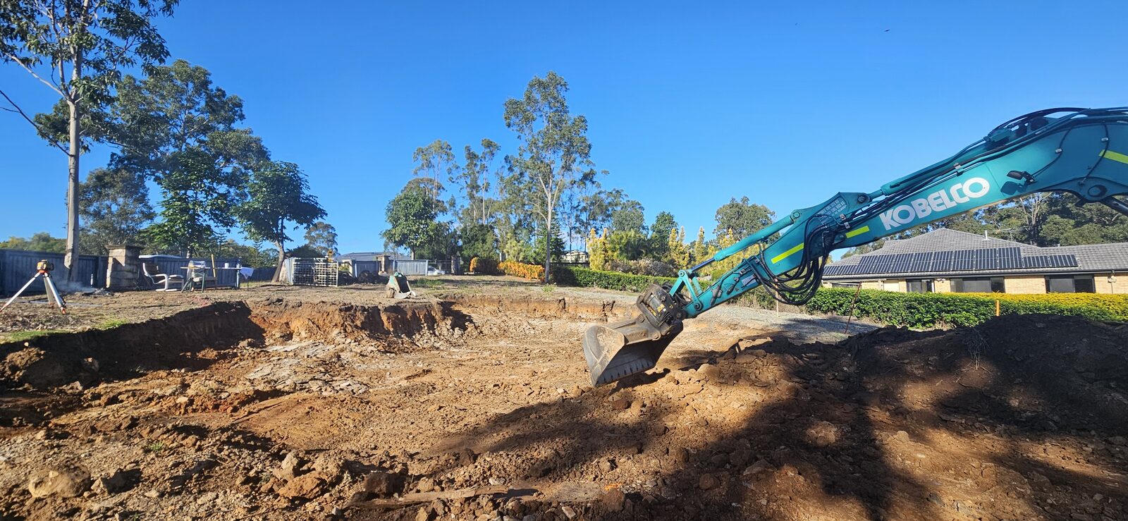 Kobelco excavator cutting into the block, starting the earthworks for the new build
