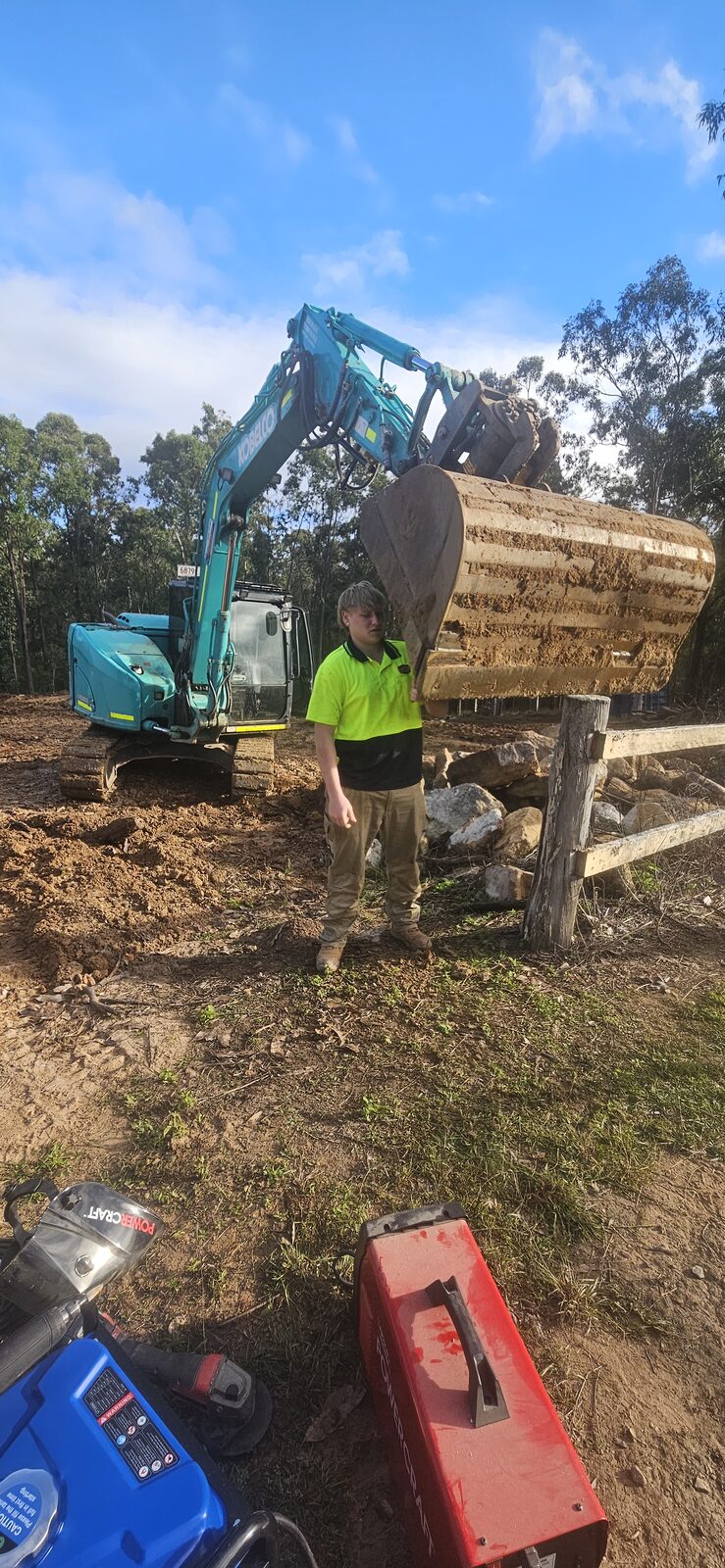 Young Sollid Solutions team member on site in front of the excavator, ready for the day