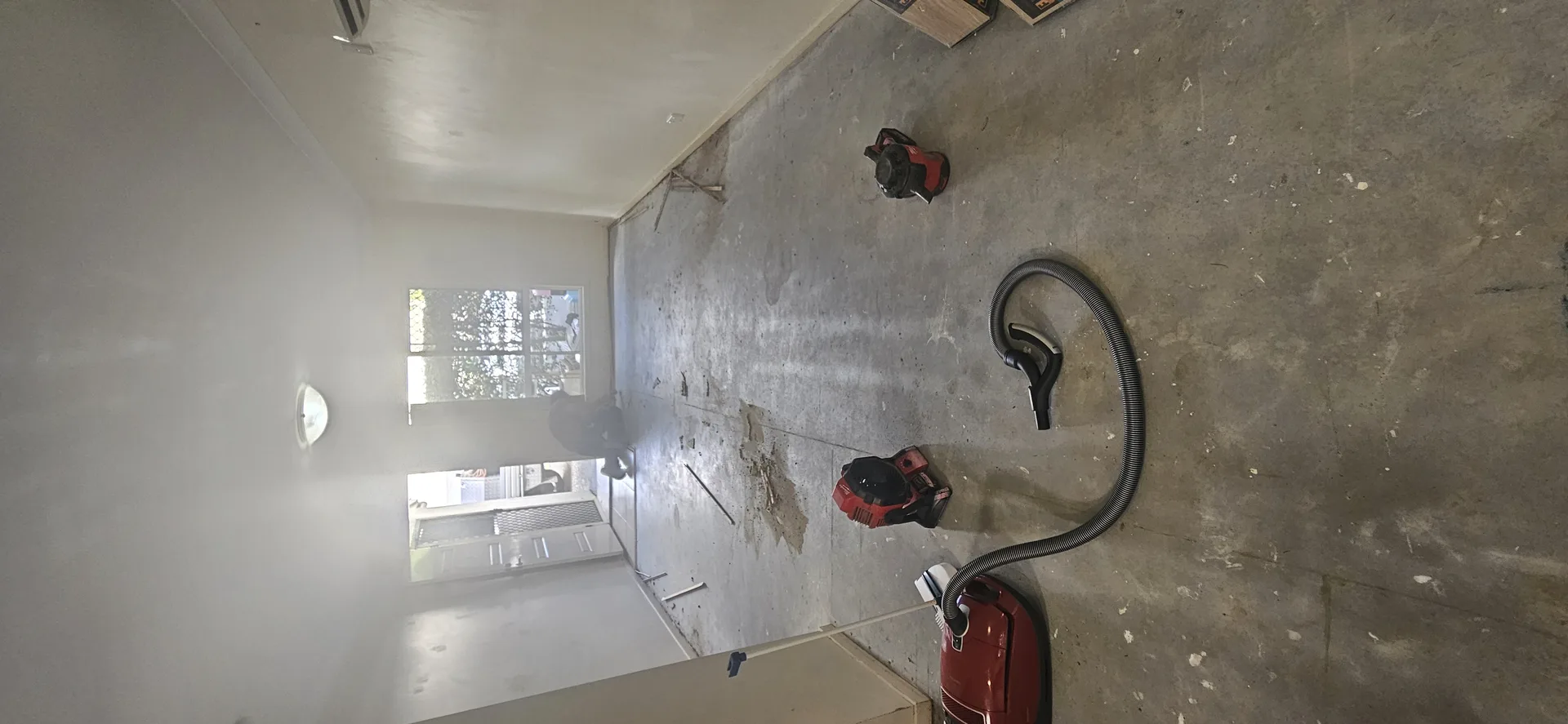 Stained concrete slab before vinyl plank floor install — Gold Coast home with vacuum and air blowers