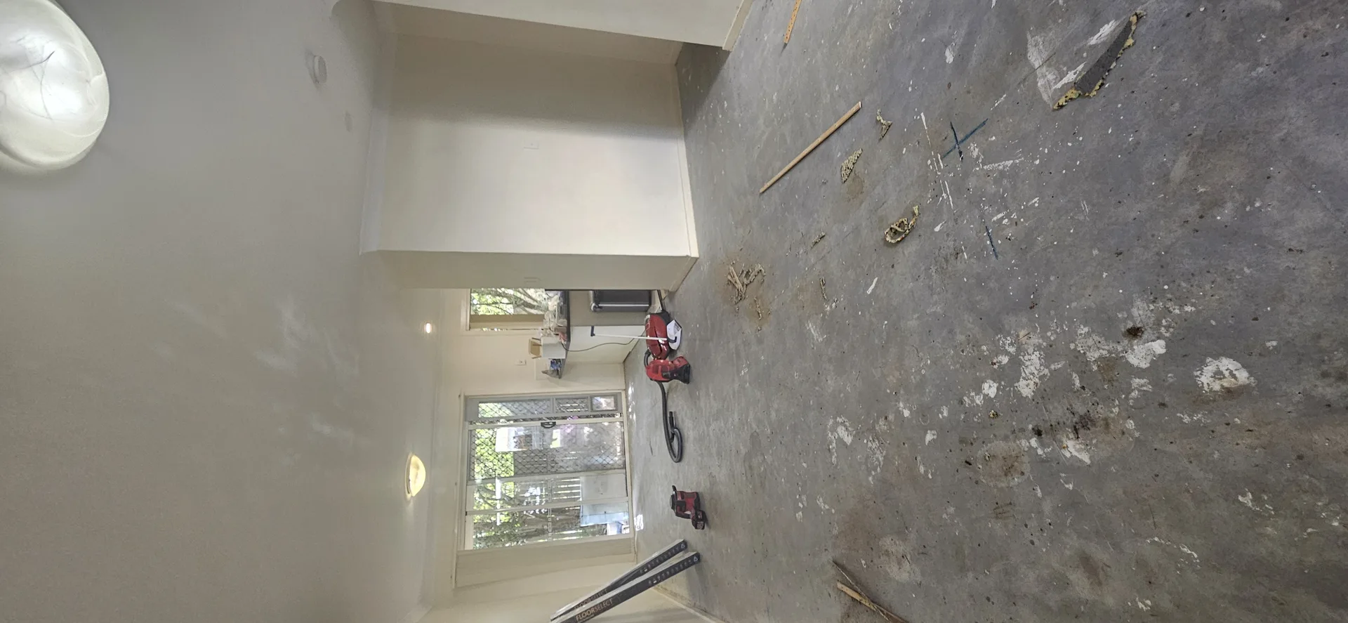Empty living room with bare concrete floor ready for vinyl plank install Gold Coast