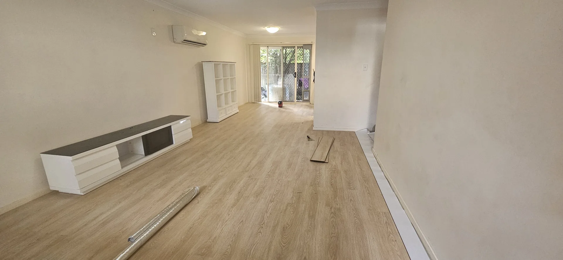 Vinyl plank flooring being installed on Gold Coast home — half-laid timber-look planks with cabinet in background