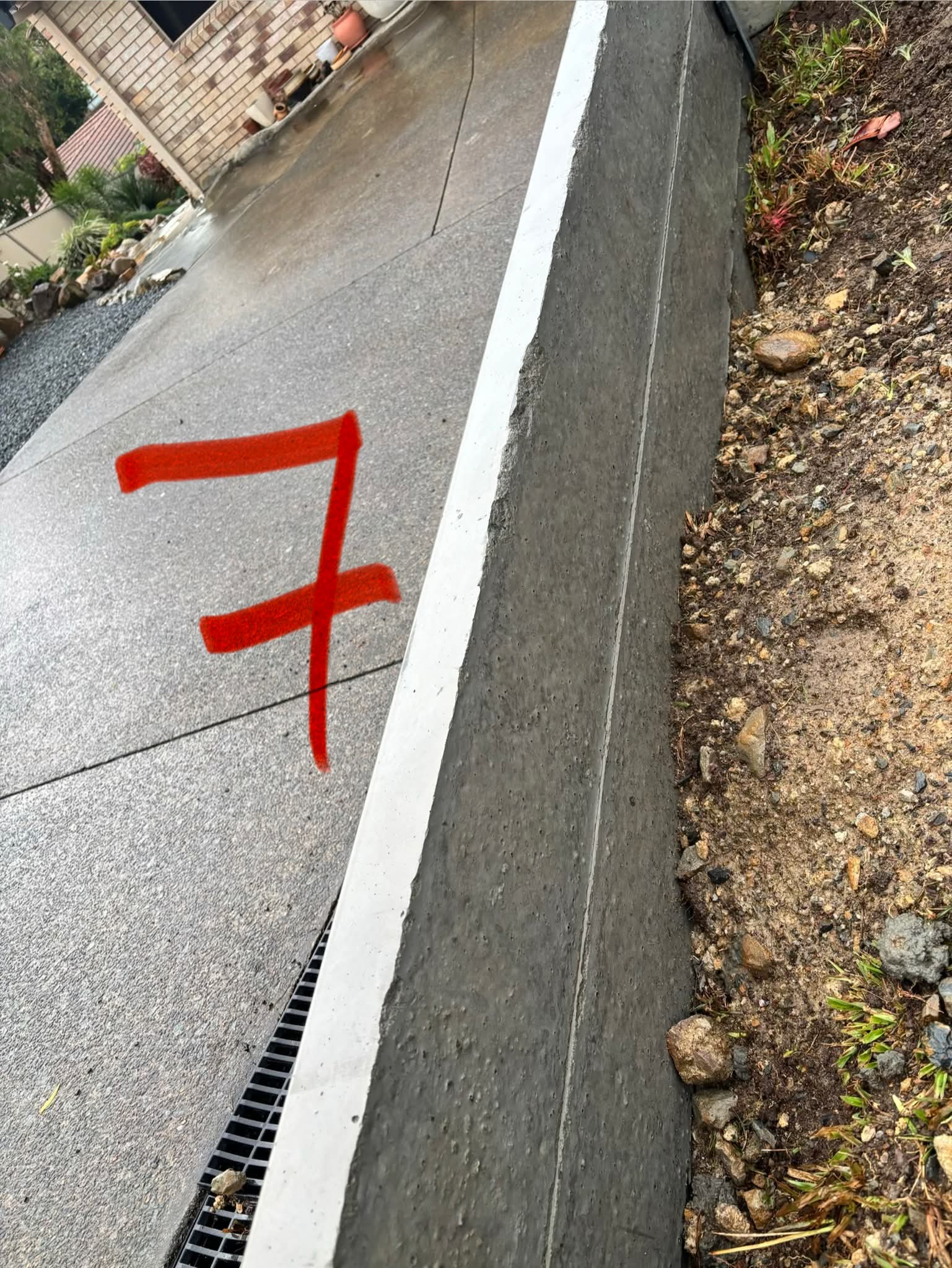 Retaining wall meeting the driveway edge with movement and gaps starting to show