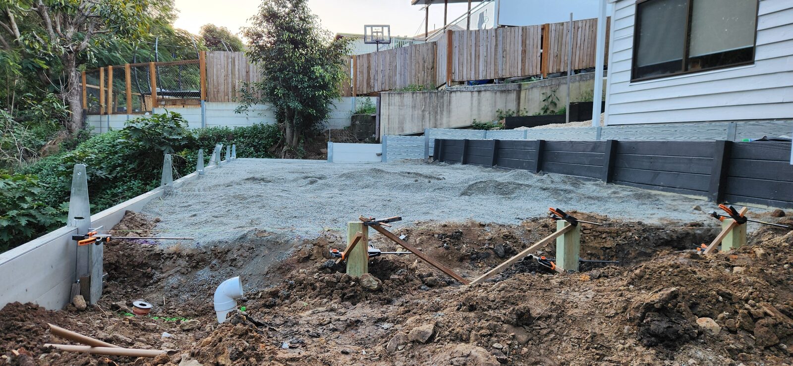 The pebble layer spread across the pool pad area between the retaining walls at Highland Park