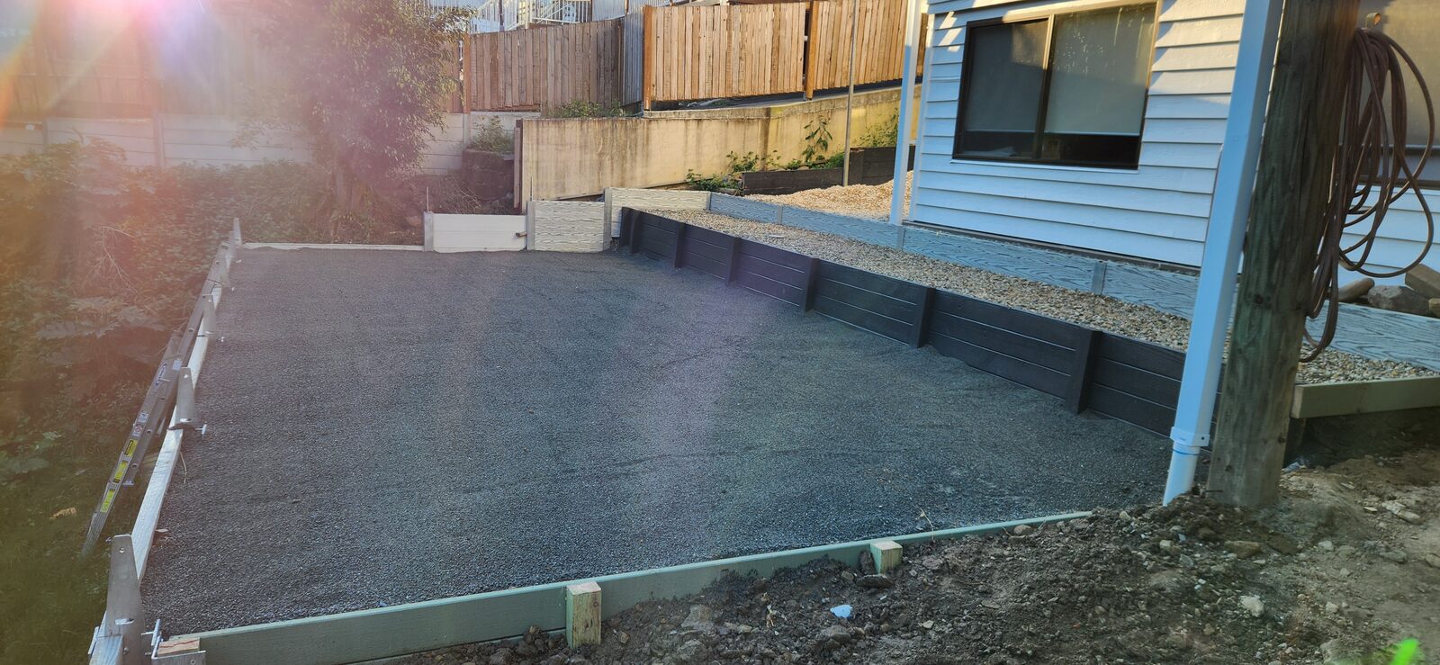 The crusher dust surface of the finished pool pad against the dark retaining walls at Highland Park